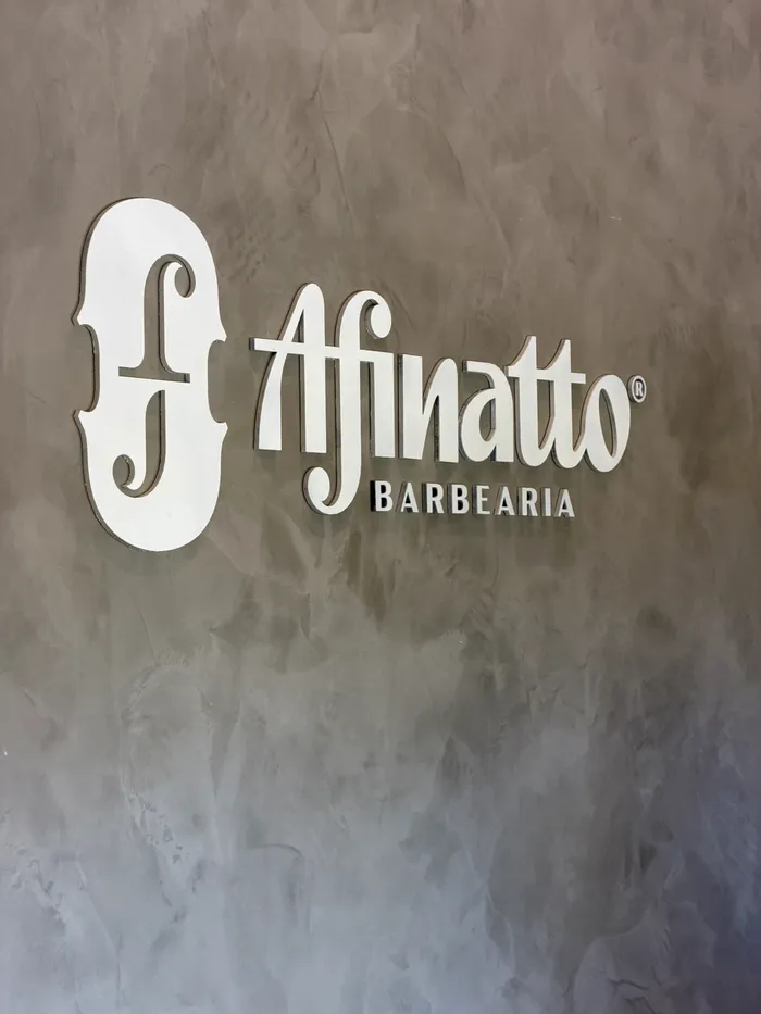 Logo da Afinatto Barbearia na parede de cimento queimado